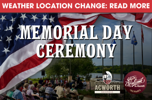 Outdoor Memorial Day Ceremony with American flags, event signage, and a seated audience; notice at top indicates a weather-related location change.