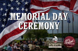 People sit outdoors by a lake with American flags and flagpoles, attending a Memorial Day ceremony in Acworth, Georgia. Large text announces the event.