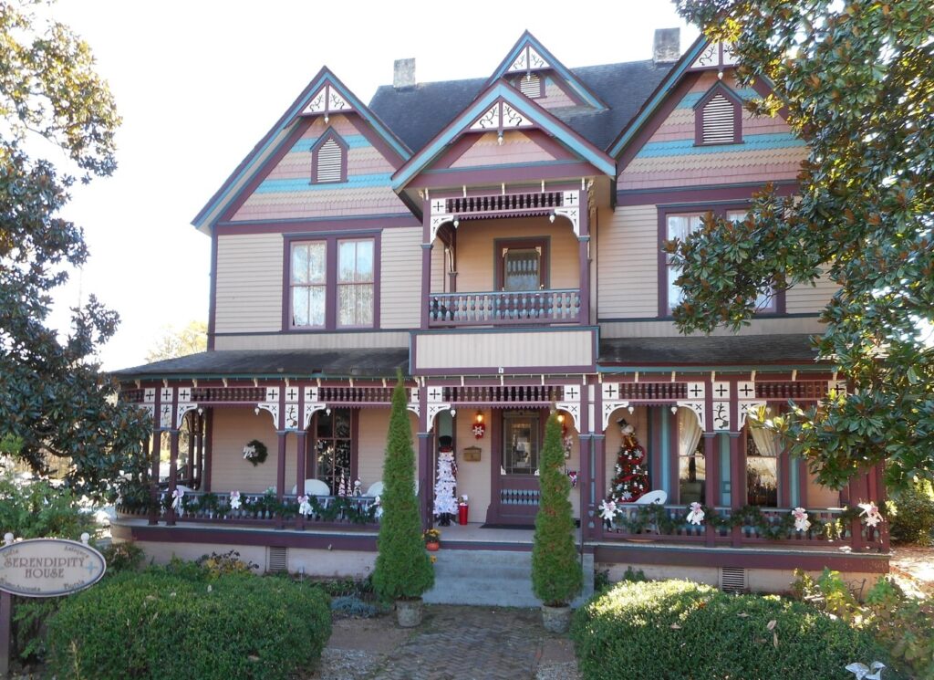 A large Victorian-style house with decorative trim, a front porch, and a sign that reads 