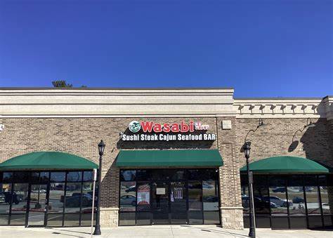 Exterior of Wasabi Sushi Steak Cajun Seafood Bar, a brick building with green awnings and clear blue sky above.