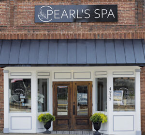 A brick building with a black sign reading "Pearl's Spa" invites you into one of the 5 must-visit Acworth spots for Valentine's Day. The facade features large windows and potted plants by the wooden door, offering a warm welcome.