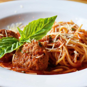 A plate of spaghetti with tomato sauce and meatballs, garnished with grated cheese and fresh basil leaves—perfect for a cozy Valentine's Day meal before exploring the 6 must-visit spots in Acworth.