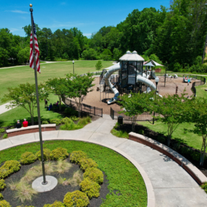 A handful of reasons to put Acworth on your travel bucket list: a charming playground with slides and climbing structures surrounded by lush greenery. Beneath the U.S. flag, enjoy paths and benches as trees border the expansive grassy area, perfect for a family day out.