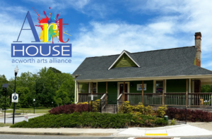 A green house with a porch under a blue sky, with a sign reading "Art House acworth arts alliance" in the top left corner.
