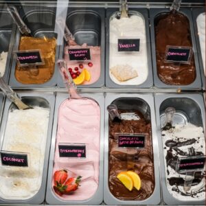 A display case containing nine flavors of gelato, each labeled—including tiramisu and cranberry—is one of the tastiest Ways to Cool Off this Summer in Acworth. Enjoy vanilla, chocolate, coconut, strawberry, stracciatella, and more.