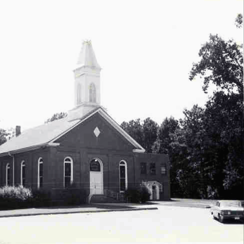 Black-and-white photo of a brick church with a steeple, arched windows, and an entrance ramp; a car is parked nearby beside trees. Learn More About Historic Acworth Locations captured in timeless detail. Black-and-white photo of a brick church with a steeple, arched windows, and an entrance ramp; a car is parked nearby beside trees. Learn More About Historic Acworth Locations captured in timeless detail.