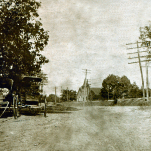 A dirt road lined with telephone poles, two early automobiles parked on the left, trees in the background, and a large building visible in the distance invite you to learn more about historic Acworth locations.