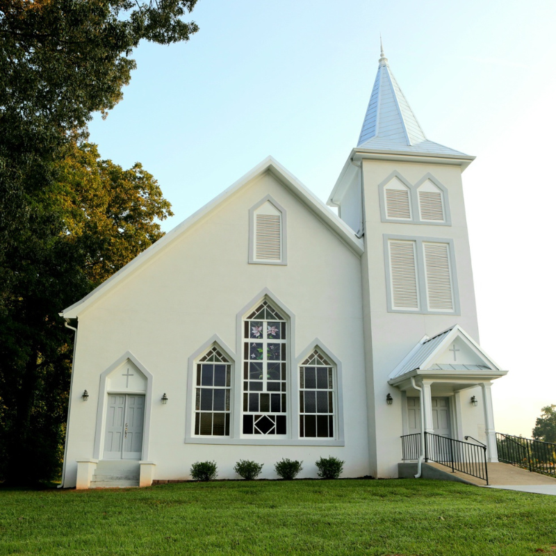 White church building with tall steeple, arched windows, and a ramp entrance, surrounded by green grass and trees under a clear sky. Learn more about historic Acworth locations like this charming landmark. White church building with tall steeple, arched windows, and a ramp entrance, surrounded by green grass and trees under a clear sky. Learn more about historic Acworth locations like this charming landmark.