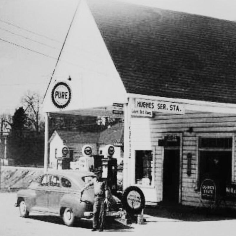 A vintage black-and-white photo of a gas station labeled “Hughes Ser. Sta.” with a “PURE” sign. A person is refueling a classic car at the pumps. Learn more about historic Acworth locations through this nostalgic scene. A vintage black-and-white photo of a gas station labeled “Hughes Ser. Sta.” with a “PURE” sign. A person is refueling a classic car at the pumps. Learn more about historic Acworth locations through this nostalgic scene.