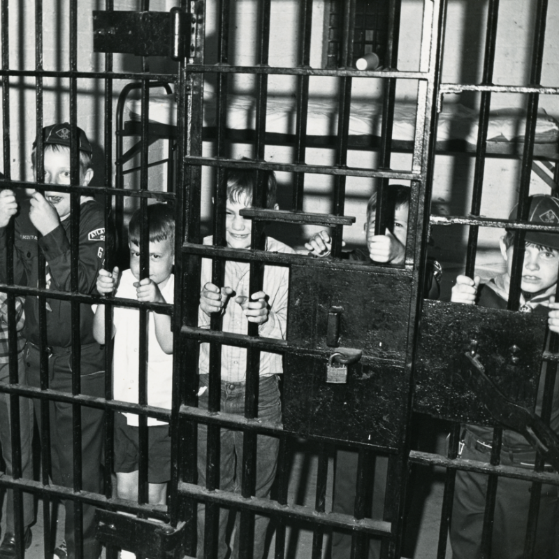 Five young boys, some in scout uniforms, stand behind bars in a jail cell, gripping the metal and looking outward. Learn more about historic Acworth locations that bring the past to life. Five young boys, some in scout uniforms, stand behind bars in a jail cell, gripping the metal and looking outward. Learn more about historic Acworth locations that bring the past to life.