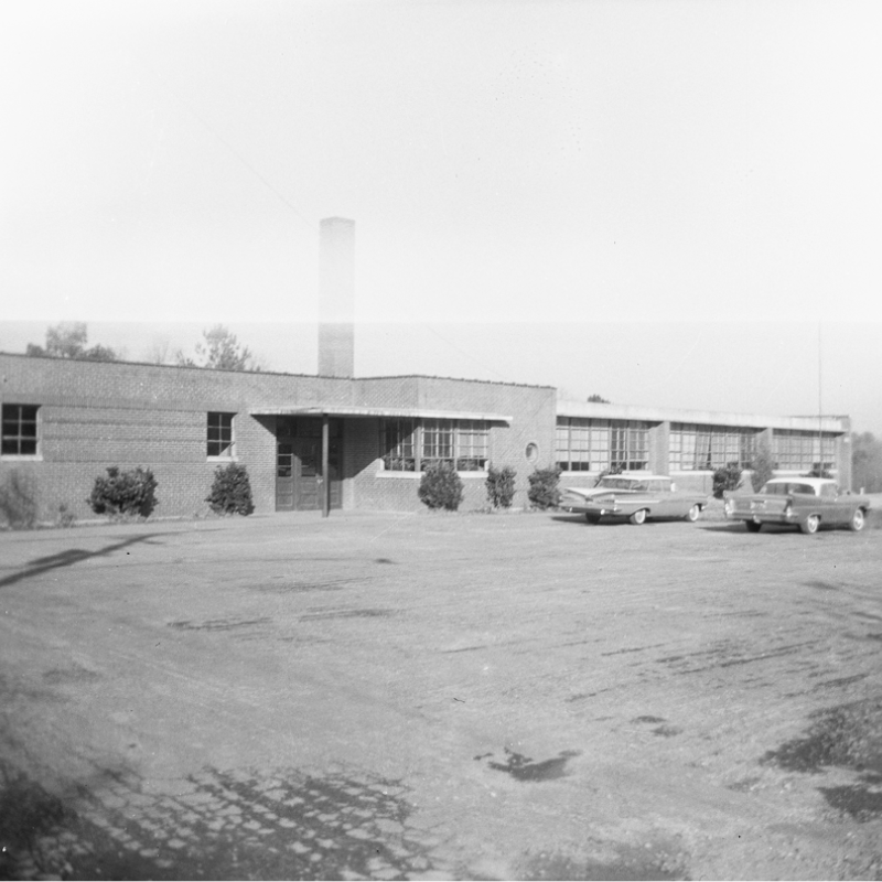 Black and white photo of a single-story brick building with a chimney, surrounded by parked vintage cars and sparse landscaping. Learn More About Historic Acworth Locations captured in this timeless scene. Black and white photo of a single-story brick building with a chimney, surrounded by parked vintage cars and sparse landscaping. Learn More About Historic Acworth Locations captured in this timeless scene.