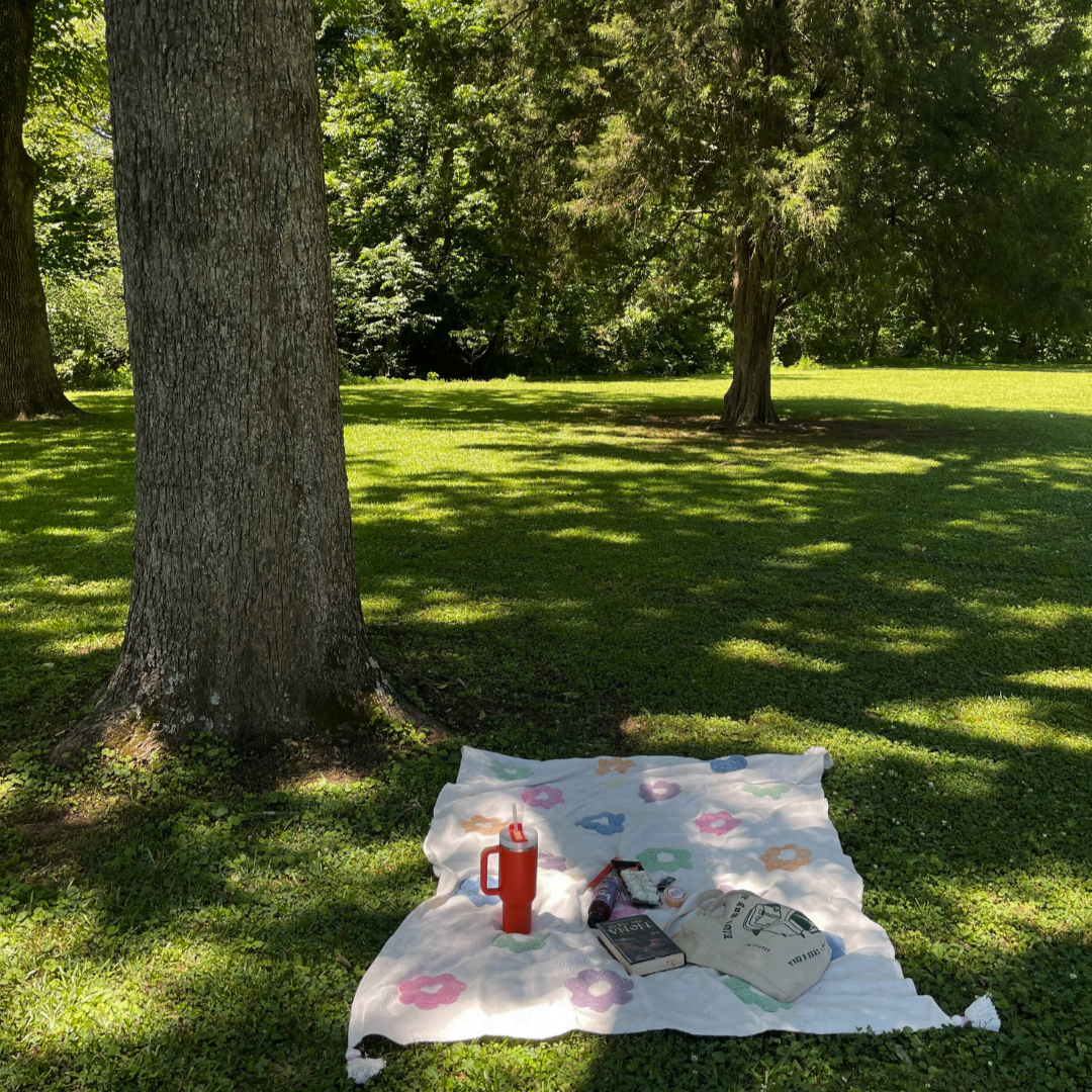 A picnic blanket with a thermos, book, and bag is spread on grass in a sunlit park with trees casting shade—an ideal scene for your end of summer bucket list. A picnic blanket with a thermos, book, and bag is spread on grass in a sunlit park with trees casting shade—an ideal scene for your end of summer bucket list.