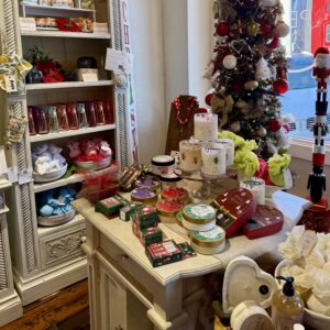 A display of bath and body products, soaps, and gift items arranged on shelves and a table next to a decorated Christmas tree in a store—your guide to Acworth gifts this holiday season.