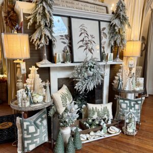 A decorated mantel with frosted greenery, framed botanical art, winter-themed pillows, and small Christmas trees creates a cozy living room—perfect for enjoying 6 Winter Combos for Fresh Food + a Good Mood in Acworth.