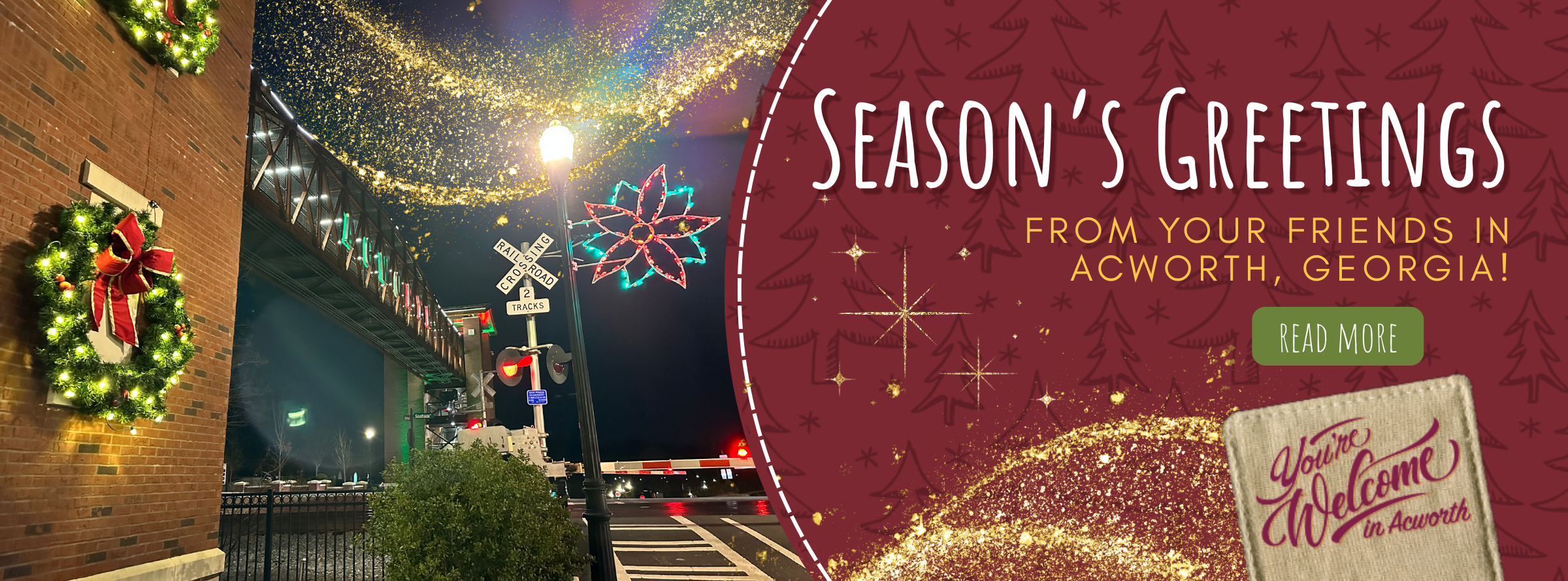 Holiday lights and wreaths decorate a street and brick building at night; text reads "Season's Greetings from your friends in Acworth, Georgia.