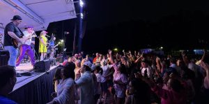 A band performs on an outdoor stage at night while a large, enthusiastic crowd listens and dances—one of the 26 Acworth-y Things to do in 2026 for live music lovers.