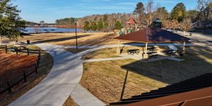 A park with paved walkways, picnic tables under a pavilion, a playground, and a lake in the background on a clear day—perfect for your list of 26 Acworth-y Things to do in 2026.