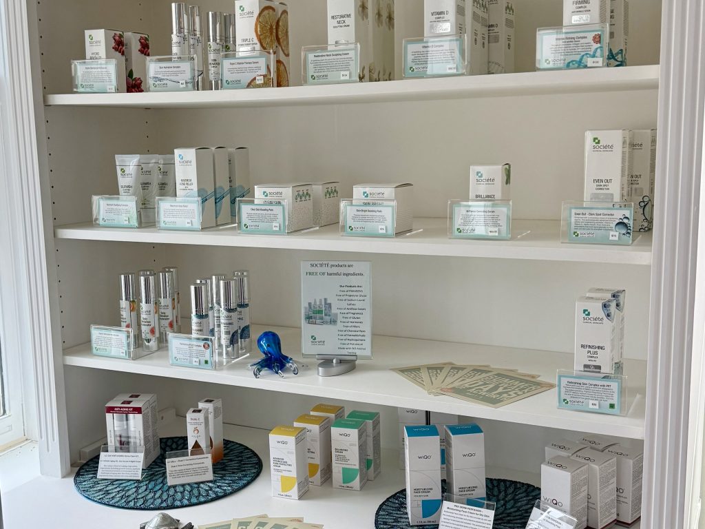 Shelves display various skincare products and informational pamphlets, organized by type and brand, in a well-lit retail setting.