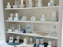 Shelves display various skincare products and informational pamphlets, organized by type and brand, in a well-lit retail setting.