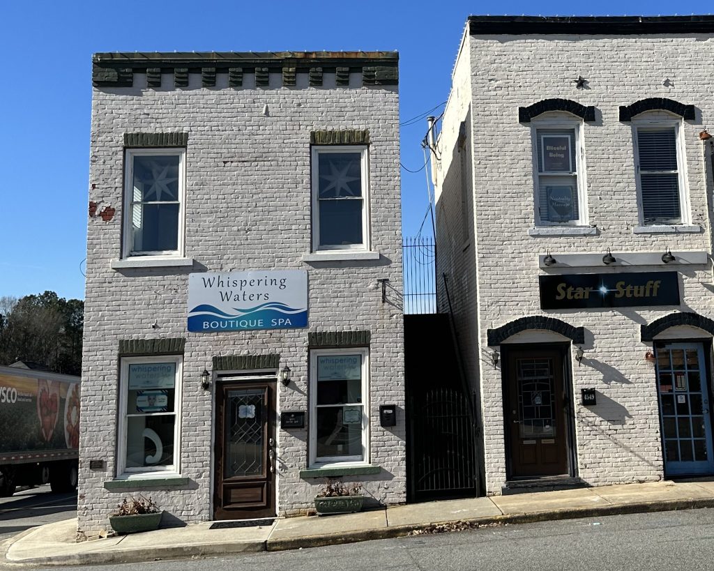 A small white brick building with a sign reading 