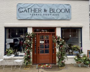 Front view of Gather & Bloom Floral Boutique with festive floral arrangements around the entrance, potted plants, and a small outdoor table and chairs—perfect for enjoying 6 Winter Combos for Fresh Food + a Good Mood in Acworth.