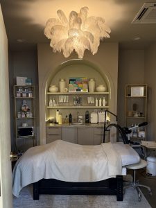 A spa treatment room with a covered bed, shelves of skincare products, and a decorative feather chandelier—perfect relaxation before exploring the 26 Acworth-y Things to Do in 2026.