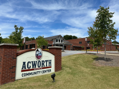 acworth community center (2) Acworth Community Center building with a sign in the foreground on a grassy area, under a blue sky with scattered clouds.