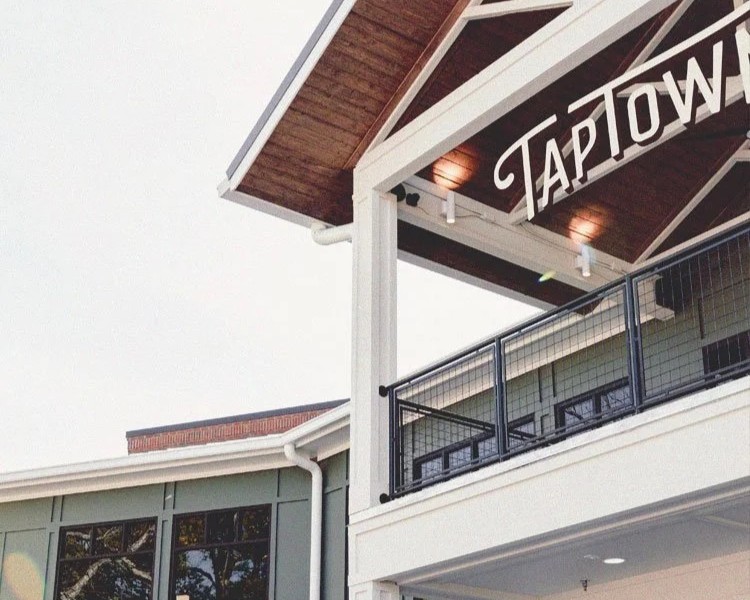 A partial view of a modern building with a balcony, railing, and a sign reading 