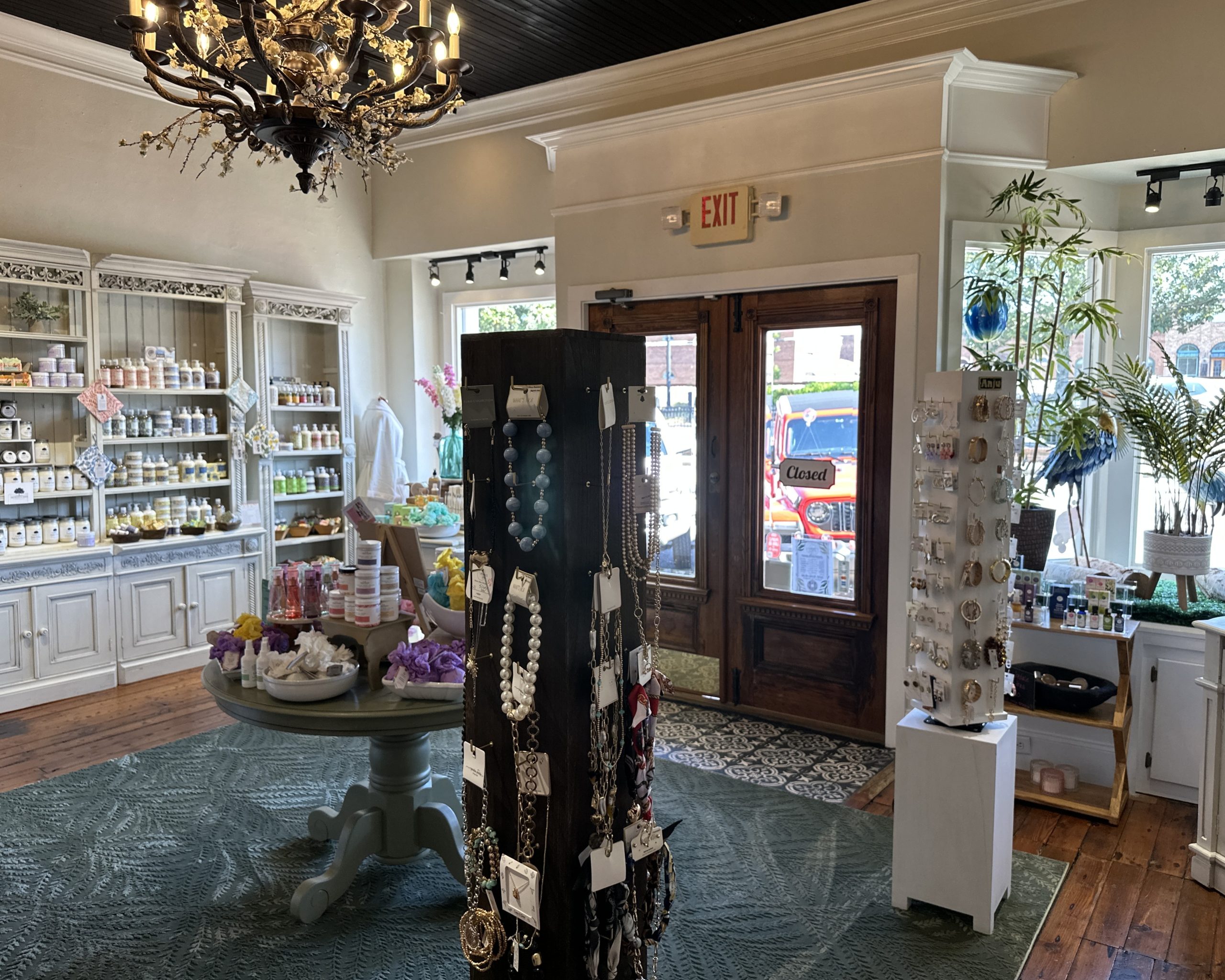 A boutique store interior at Pearl's Spa in Downtown Acworth features shelves of soaps, jewelry display stands, and decorative items. Sunlight streams through the windows, while a “Closed” sign hangs on the front door.
