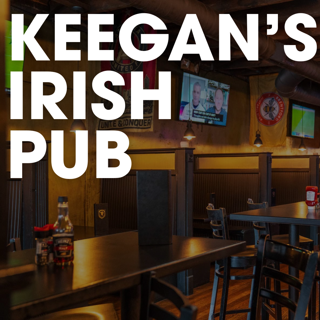Interior of Keegan’s Irish Pub, a spot to watch football in Acworth, featuring dark wooden tables, booths, sports pennants, and a television screen.