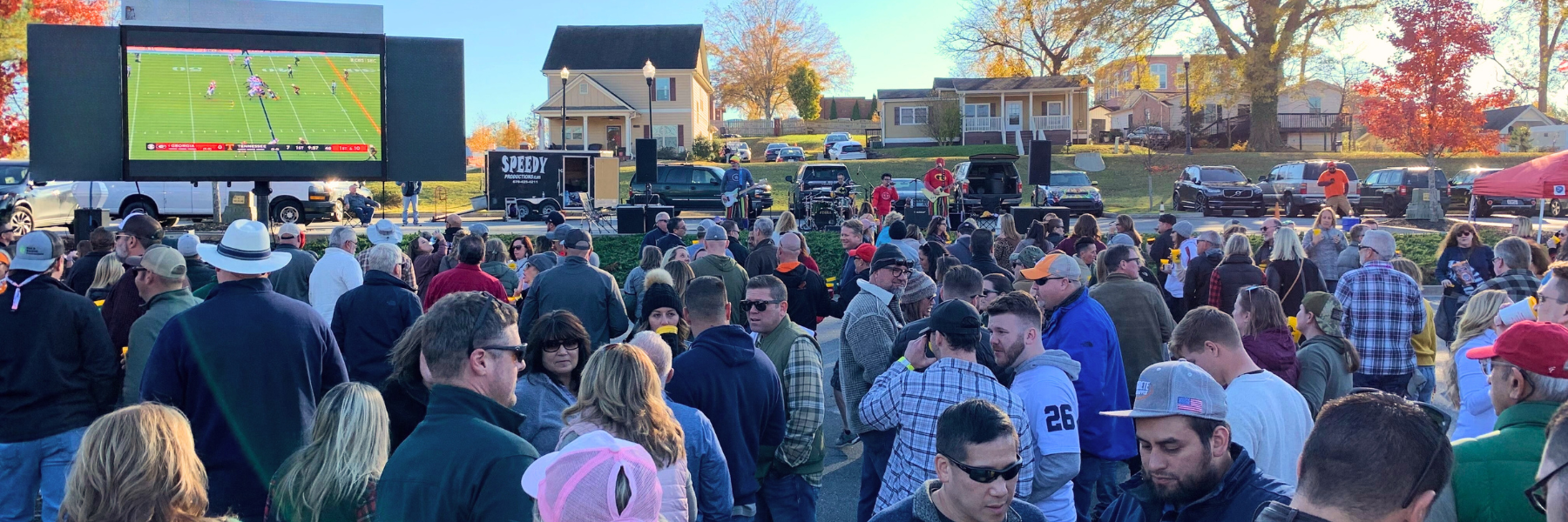 A crowd gathers in an Acworth parking lot to watch a football game on a large outdoor screen this fall.