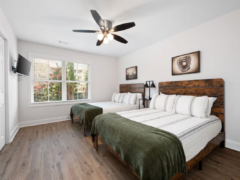Bedroom with two queen beds featuring wooden headboards, white striped bedding, and green throws.
