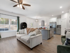 Open-concept living room and kitchen with a beige sofa, kitchen island, and hardwood floors.